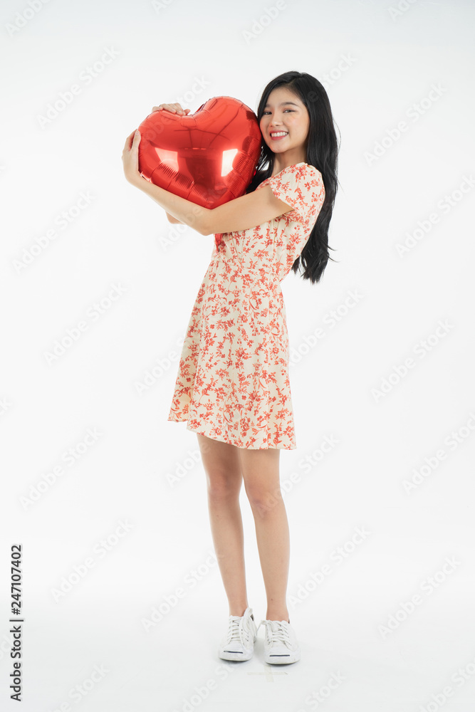 Asian young woman in red dress red ballon heart. Young woman holding it with being excited and surprised holiday present isolated white background.concept love surprise valentine day. Asian young woman in red dress red ballon heart. Young woman holding it with being excited and surprised holiday present isolated white background.concept love surprise valentine day.