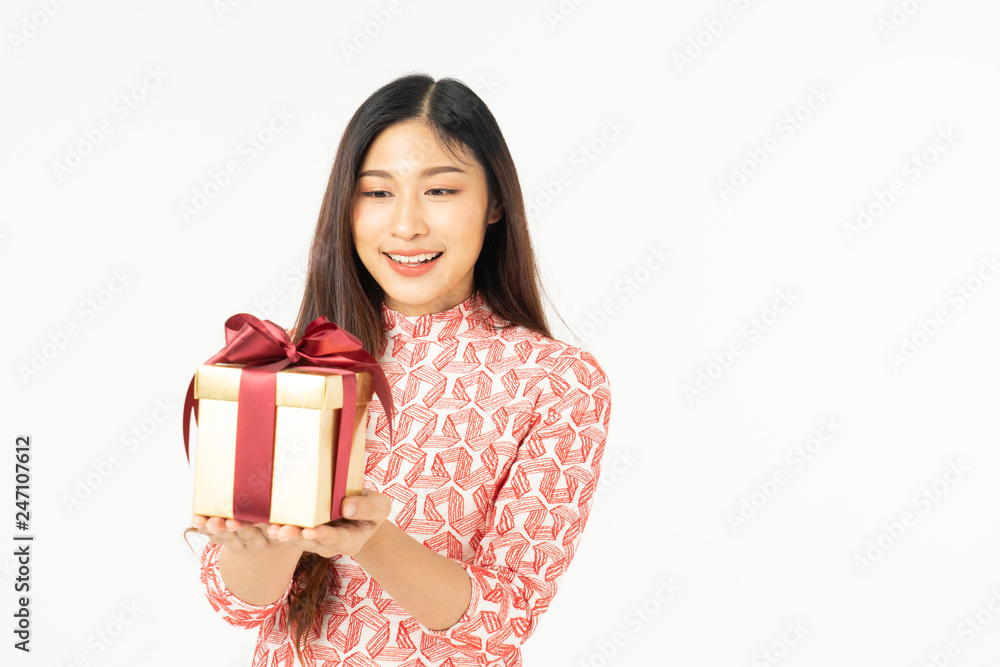 Photo of asian curious woman in red dress rejoicing her birthday or new year gift box. Young woman holding gift box with red bow being excited and surprised holiday present isolated white background Photo of asian curious woman in red dress rejoicing her birthday or new year gift box. Young woman holding gift box with red bow being excited and surprised holiday present isolated white background