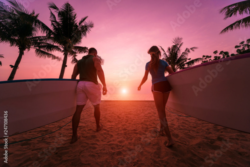 Canvas Print Two young surfers going into the sea with surf boards