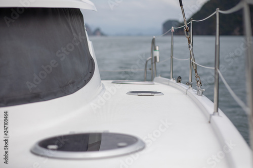 View from board of cutter with blue water and sea foam with a boat seen / yachting sport on a summer sunny day with blue sky/ Concept of speed /boat interior