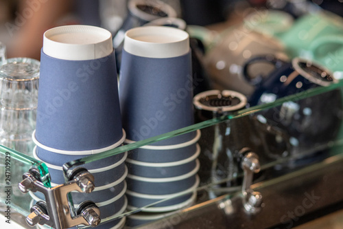 A stack of blue paper cups and coffee cups lies on the rack in a row. close up