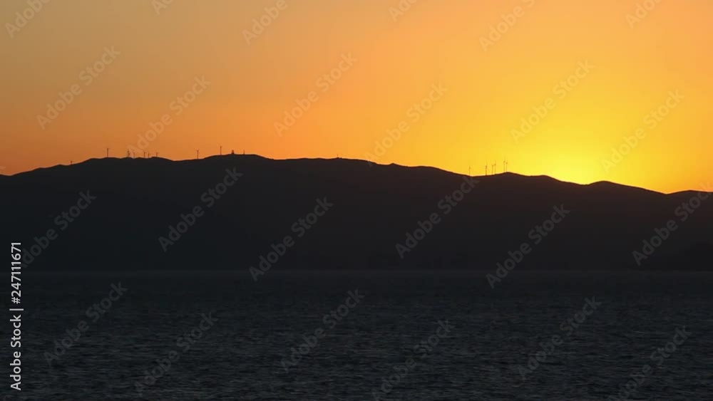 Silhouette of the Greek coast at sunset with wind turbines Silhouette of the Greek coast at sunset with wind turbines