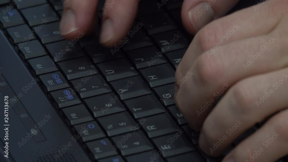 Hands are shown typing on a slowly rotating laptop computer keyboard in a closeup view. Hands are shown typing on a slowly rotating laptop computer keyboard in a closeup view.