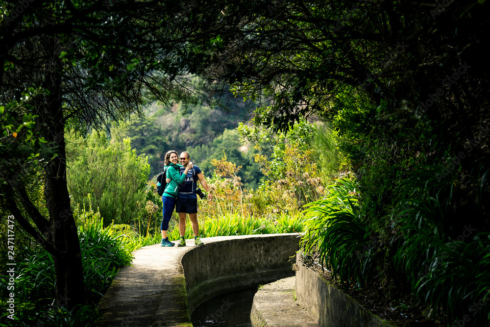Portrait of just married couple walking by levana on Madeira island, up in mountains. Hiking by the trail among green, tropical and old forests. Portugal.