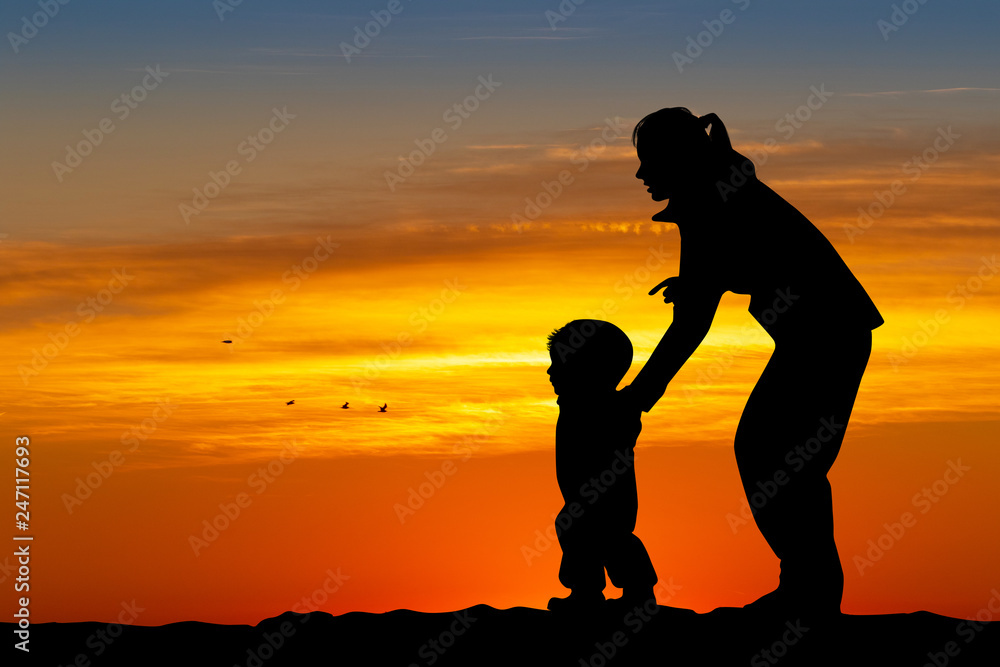 mom plays with the child on the snow at sunset