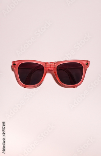 Red bright sunglasses on a pastel pink background. Summer time, party and vacations concept.