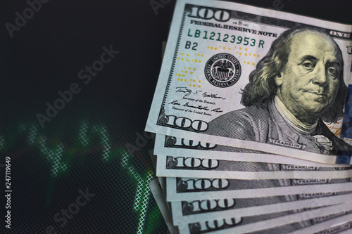 US dollar bills on a background with dynamics of exchange rates. Trading and financial risk concept