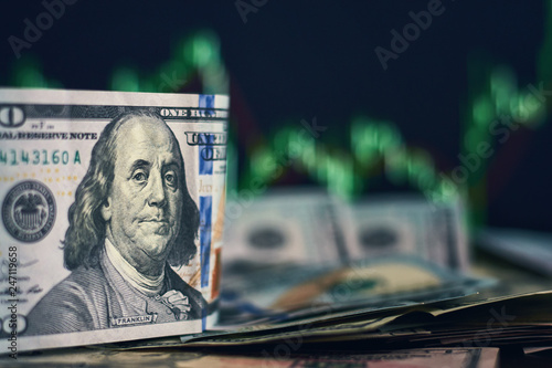 US dollar bills on a background with dynamics of exchange rates. Trading and financial risk concept