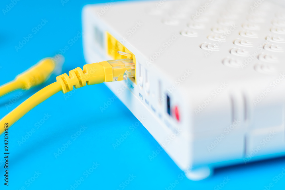 home wireless router with ethernet cable plugged in on blue background, closeup home wireless router with ethernet cable plugged in on blue background, closeup