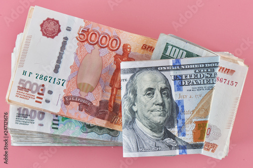 Rubles and dollars. Russian and American paper money on a pink background