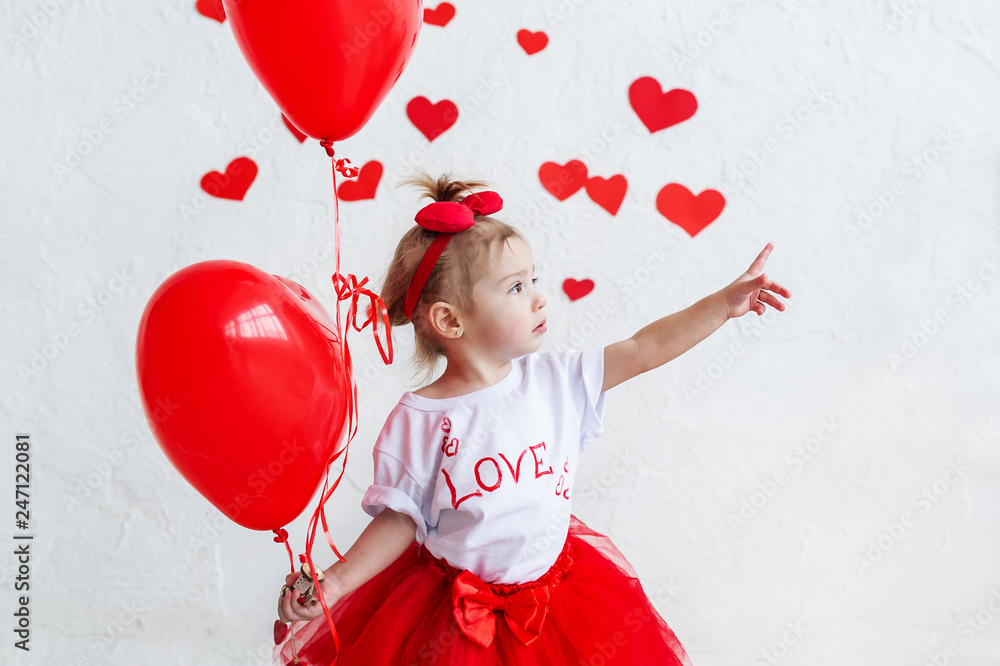 Pretty cute baby girl holding heart-shaped balloons on saint valentine's day
