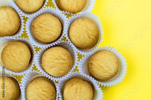 Cookies in paper baskets on yellow background