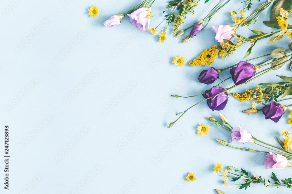 Naklejka premium Flowers composition. Yellow and purple flowers on pastel blue background. Spring, easter concept. Flat lay, top view, copy space