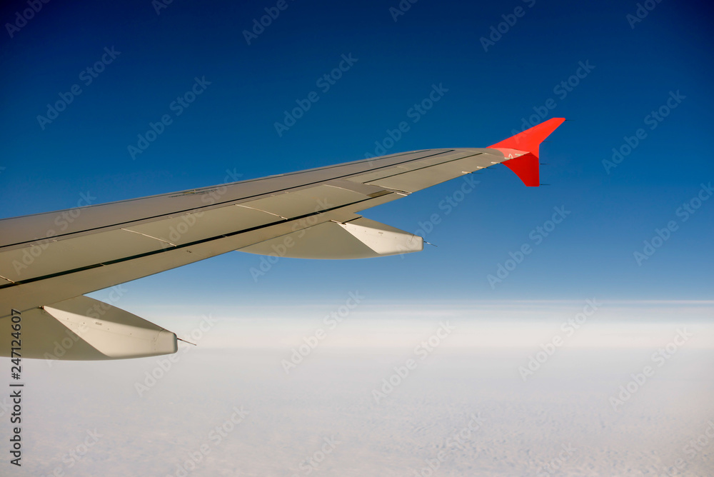 Fototapeta premium wing of airplane flying above clouds