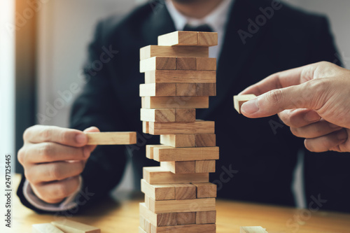 Strategic thinking and risk by business people pulls wooden blocks from the group.