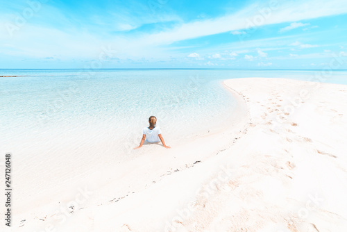 Woman sunbathing on scenic white sand beach  rear view  sunny day  turquoise transparent water  real people. Indonesia  Wakatobi islands