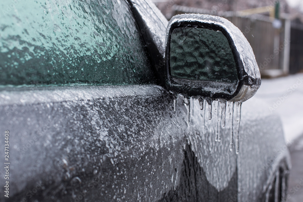 Frozen mirror of a car with iciclas on it in winter timea