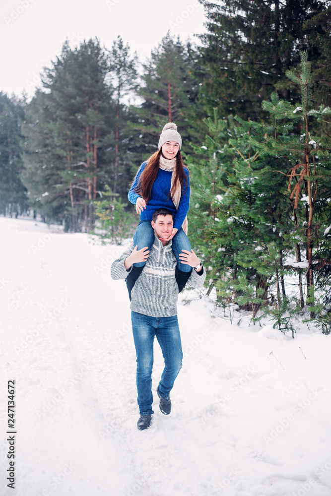 Happy loving young couple walking in snowy winter forest