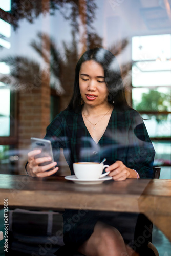 Girl having coffee and using phone in the bar