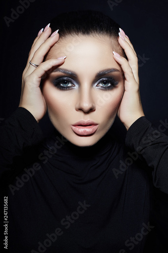 Classic Smokey makeup on woman face  beautiful big eyes. Fashion Perfect makeup  expressive eyes on girl face  smooth black eyebrows  licked brunette hair. Portrait of a woman on a dark background