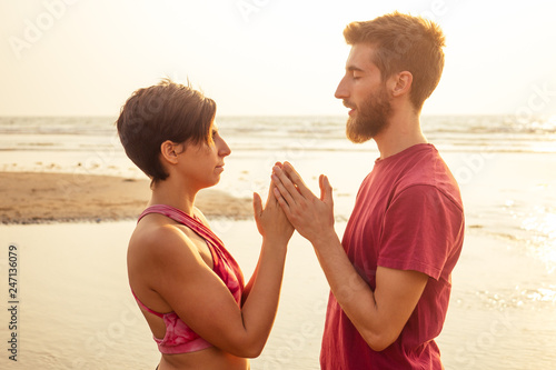 muladhara swadhisthana manipula tantra yoga on the beach man and woman meditates sitting on the sand by the sea at sunset romantic Valentine's Day.couple practicing yoga steam photo