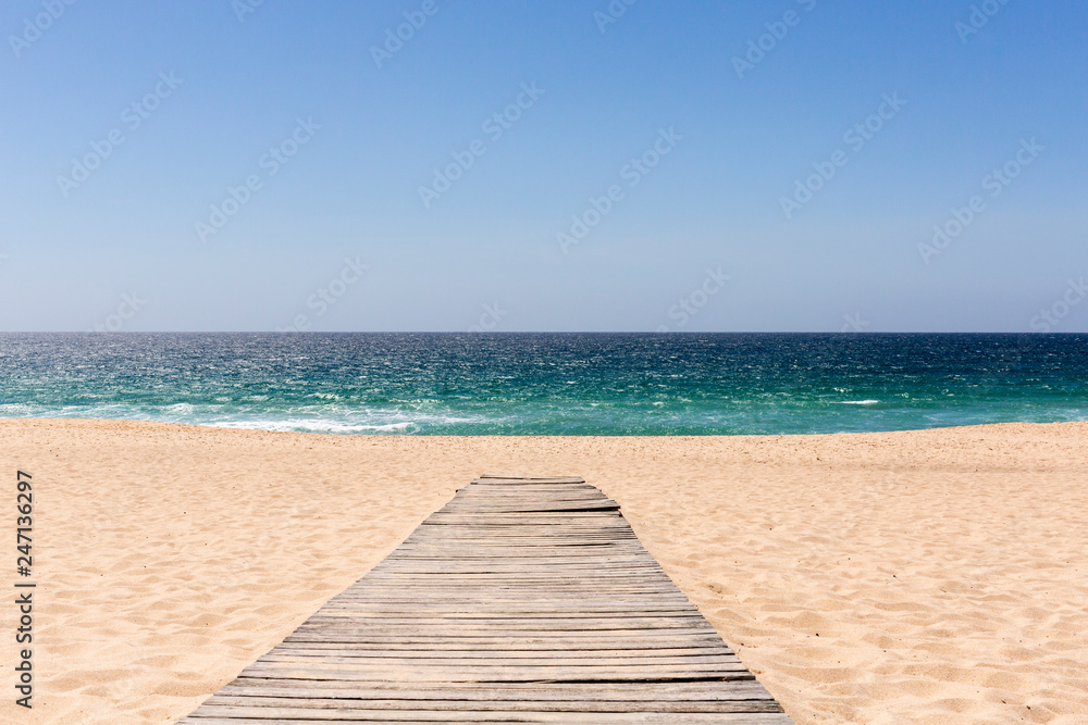 Wooden board walk leading to a sandy beach and the sea