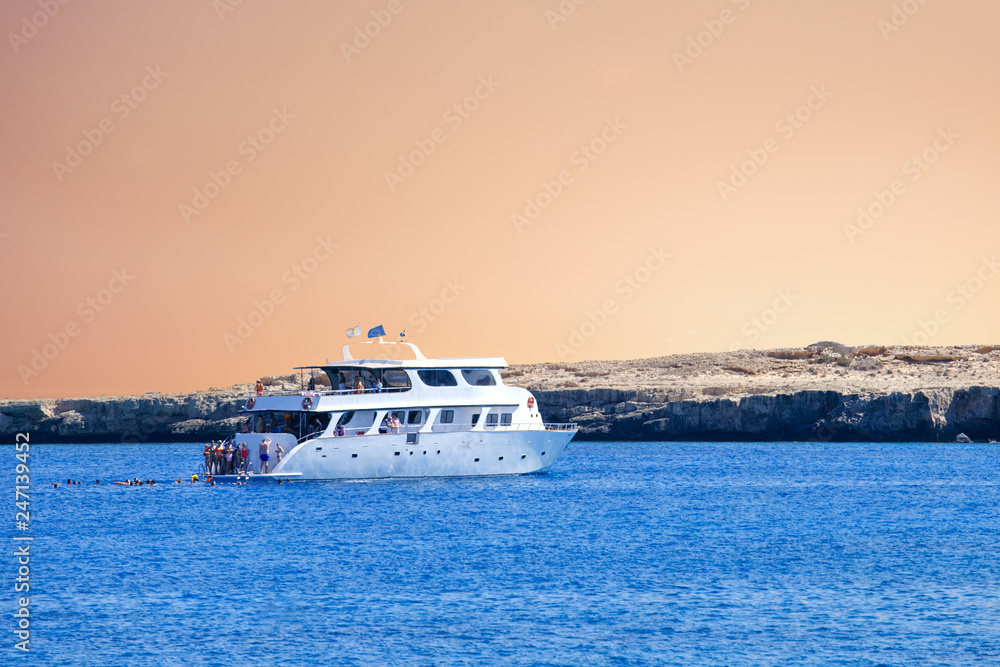 Yacht in blue lagoon on sunset. Tourist boat in Cyprus. Vacation, holiday background or concept.