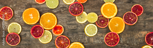 many different juicy and healthy citrus fruits lie together on an old, vintage wood background