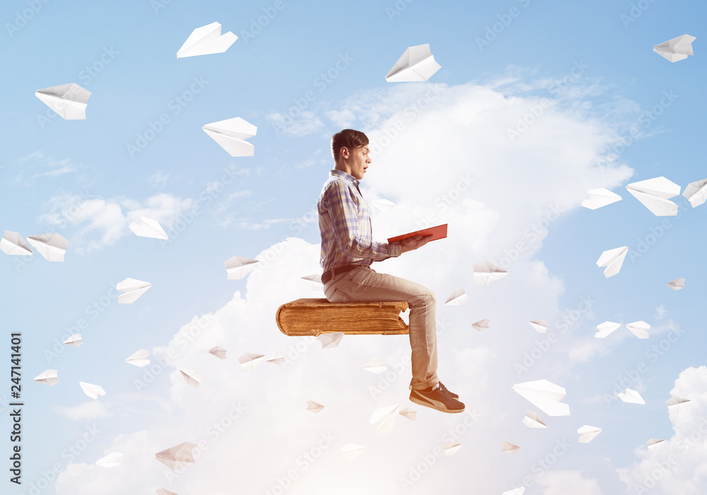 Handsome man student reading book and paper planes flying around Handsome man student reading book and paper planes flying around