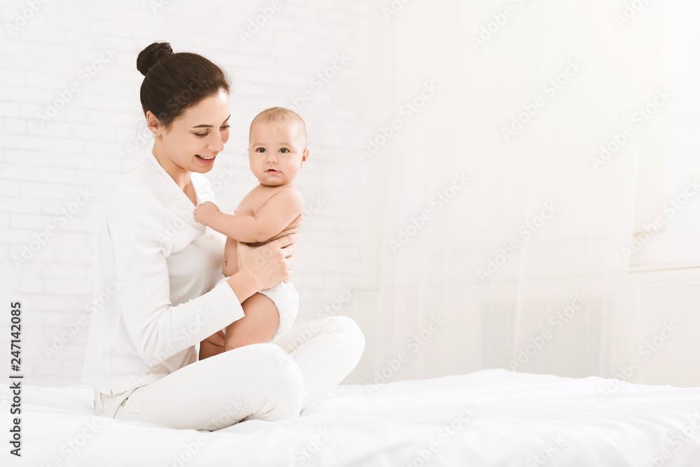 Young mother sitting with baby on bed Young mother sitting with baby on bed