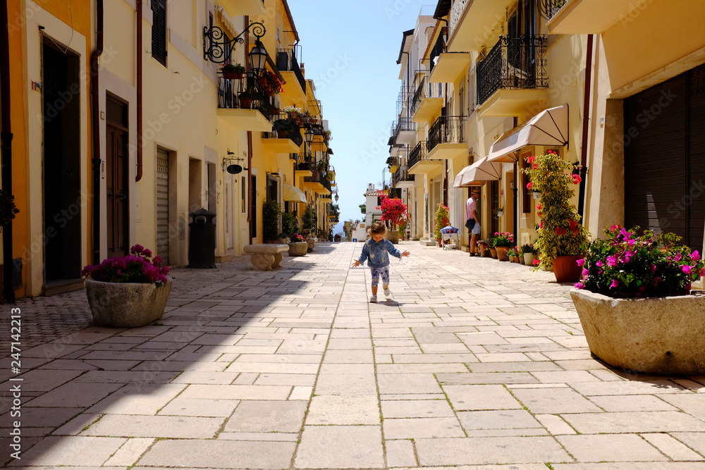 A little girl runs happily in the picturesque Italian village. San Felice Circeo, Lazio, Italy