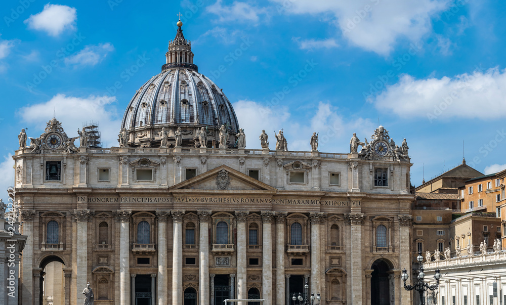 panoramic front view on Dome of St. Peter's Basilica with statues of apostles chapel with bell and old clock in Vatican City, Italy