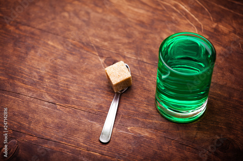 absinthe shot glass sugar spoon lemon wooden table  photo