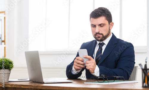 Businessman sending mail to partner on smartphone