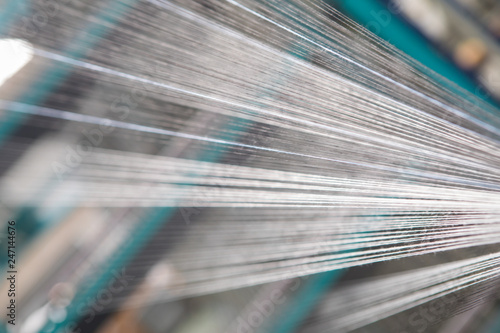 Close up macro detail of Yarn thread lines running in the weaving loom machine. Yarn bobbins making in a textile factory.