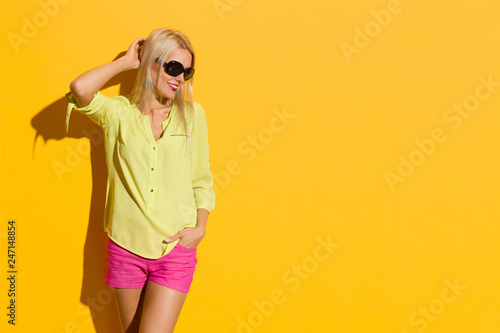 Smiling Blond Woman In Vibrant Clothes And Sunglasses Is Looking Away