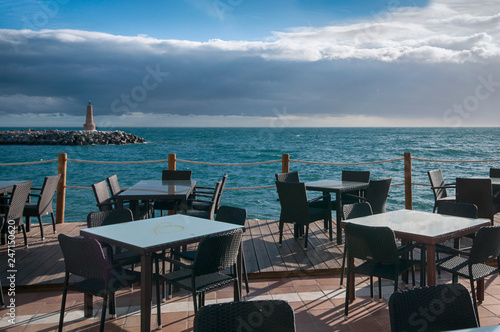 black table and chairs in the restaurant on the beach against the lighthouse © Дмитрий Абрамов