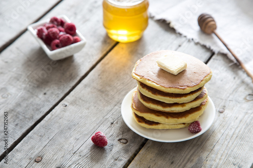 Sweet Homemade Stack of Pancakes with Butter, raspberryes and Honey for Breakfast photo