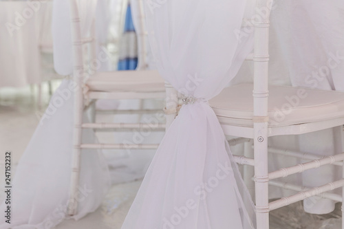 Beautiful decoration of the wedding party, white fabric on the chairs, close-up