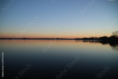 Sunset is reflecting over the water of the Rottemeren and river Rotte at Zevenhuizen close to Rotterdam in the Netherlands photo