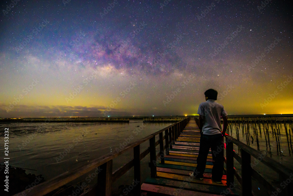 The man sitting at the bridge with milky way on the sky
