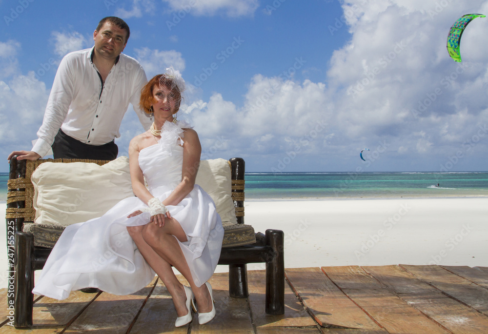 Happy newlyweds on their wedding day on a tropical beach on the ocean.