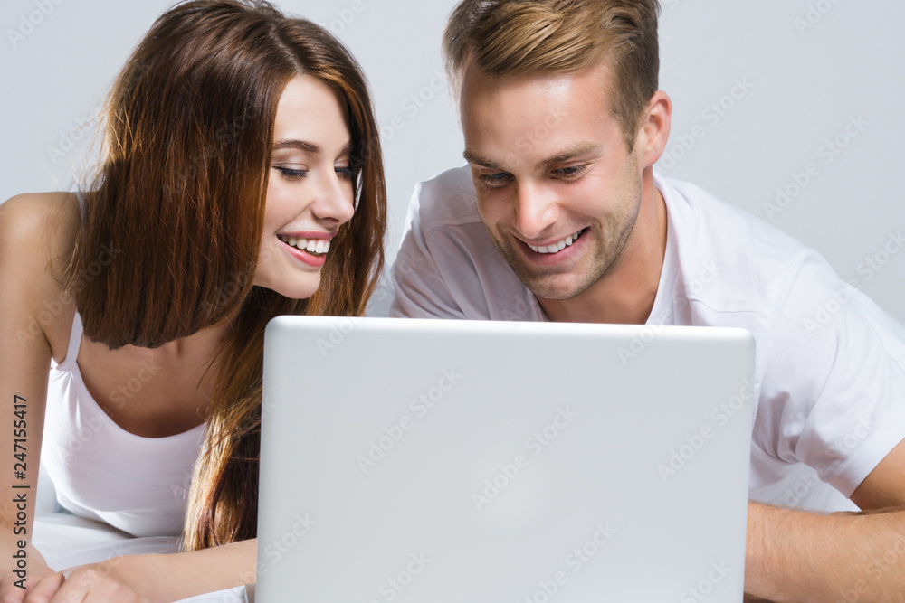 Couple using laptop, on bed