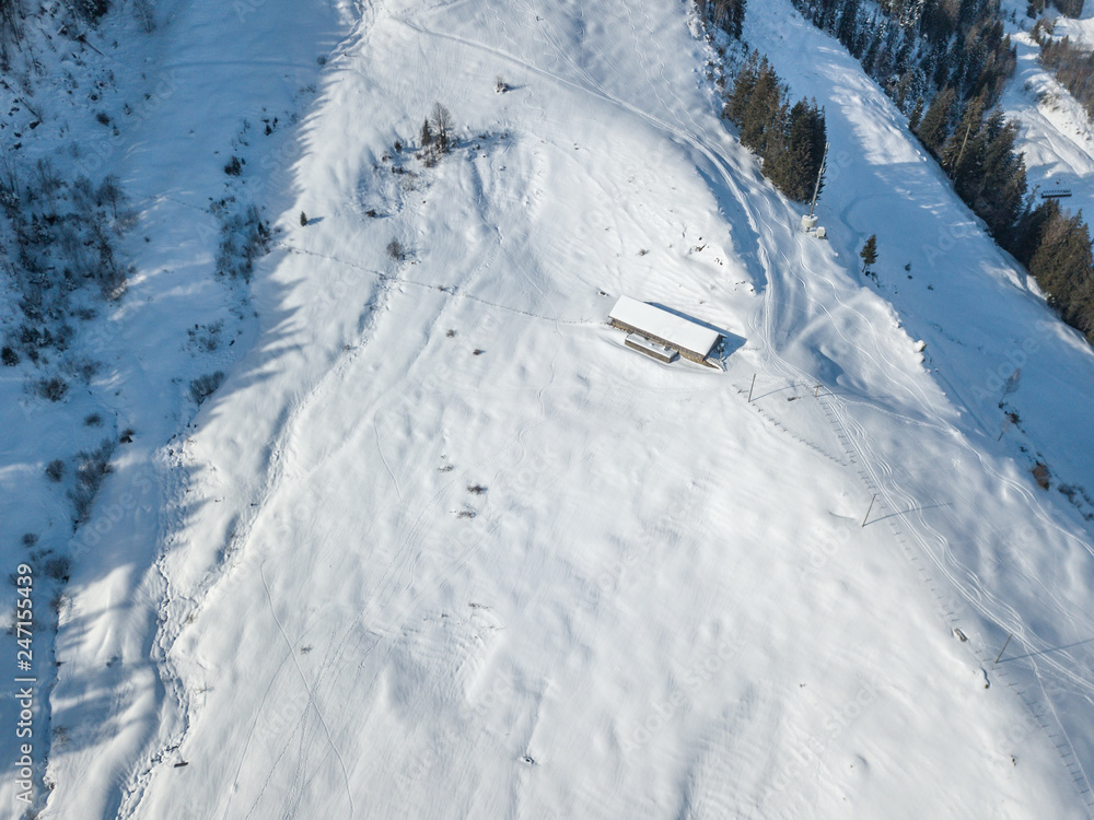 Obraz premium Aerial view of cottage in snow. Remote building with snow covered roof in Switzerland.