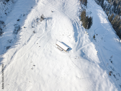 Aerial view of cottage in snow. Remote building with snow covered roof in Switzerland.