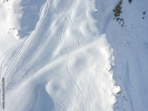 Aerial view of ski tracks in snow. Backcountry skiing in powder, leaving trails in snow.