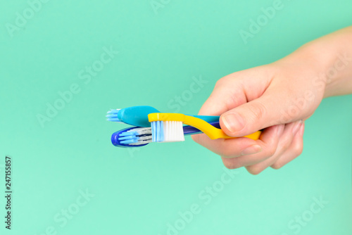 The woman holds toothbrushes in her hand on a green background.