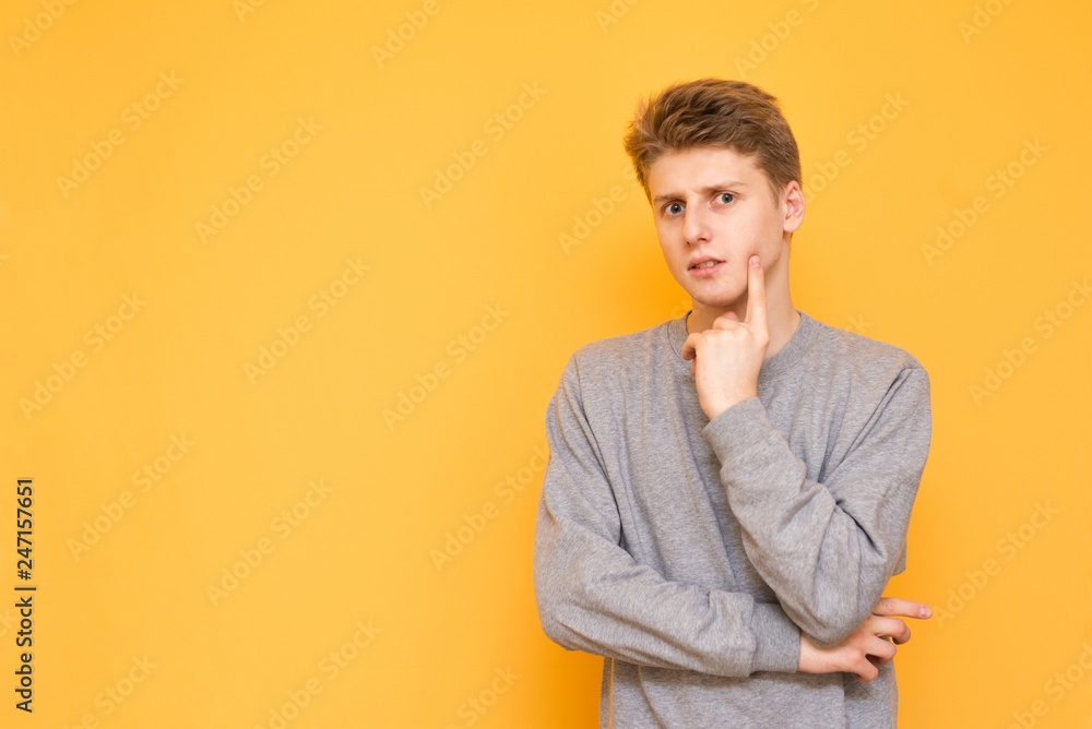 Portrait of an attractive young man thoughtfully looking into the camera on a yellow background. A serious guy in casual clothing is isolated on a yellow background. Copyspace Portrait of an attractive young man thoughtfully looking into the camera on a yellow background. A serious guy in casual clothing is isolated on a yellow background. Copyspace
