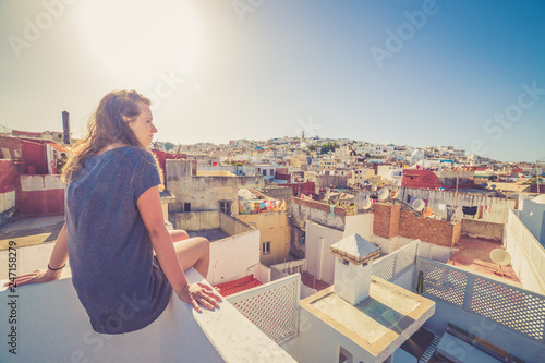 Tourist girl watching the cityscape of the medina of Tanger, Morocco. Colors of sunset