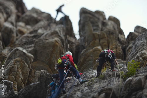  A group of climbers are on a self-insurance against the background of high rock towers. Tilt-Shift effect.
